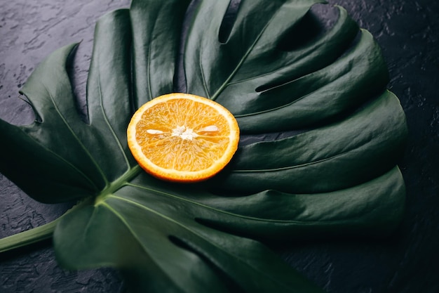 An orange on green tropical leaf Monstera houseplant on black background Eco friendly photo