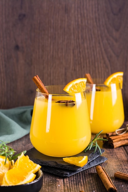 Orange grog with cinnamon and cardamom in glasses on the table Homemade drinks Vertical view