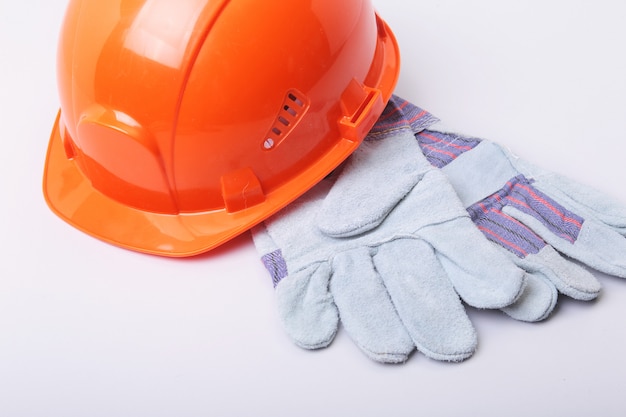 Orange hard hat, goggles and safety gloves on a white background.