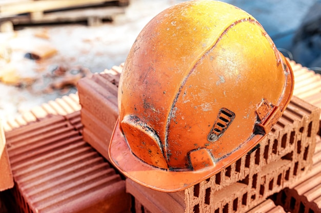 An orange hard hat or helmet for a worker lies on the bricks Safety in construction Construction site and protective equipment