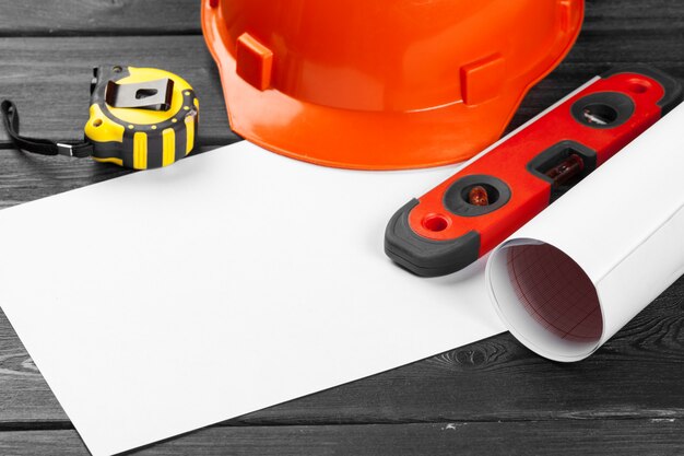 orange hardhat and variety of repair tools over wooden background