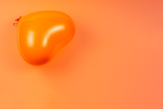 Orange heart ballon on orange background. Copy space.