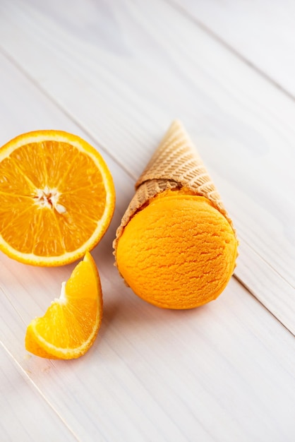 Orange ice cream in a waffle cone on a wooden table