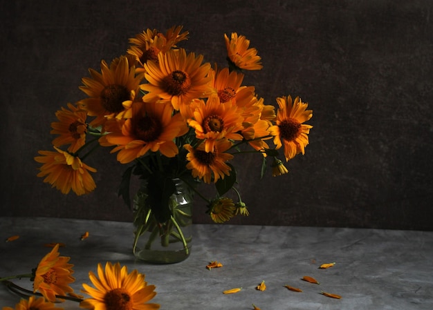 Photo orange jerusalem artichoke flowers in a vase on a dark background