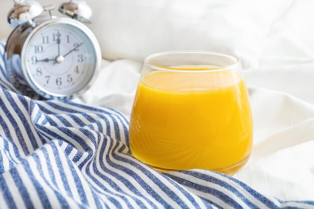 Orange juice and alarm clock on the bed