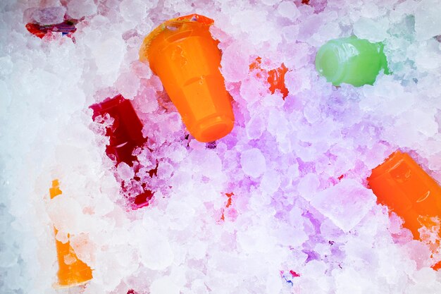 Orange juice and colorful sweet water on ice crystals