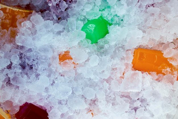 Orange juice and colorful sweet water on ice crystals