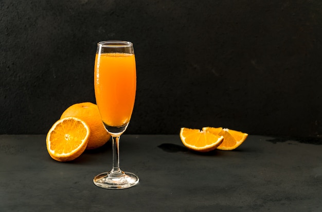 Orange juice glass for drink on dark floor and half on black