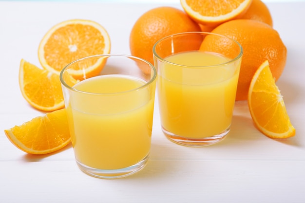 Orange juice in a glass oranges and orange slices on the table