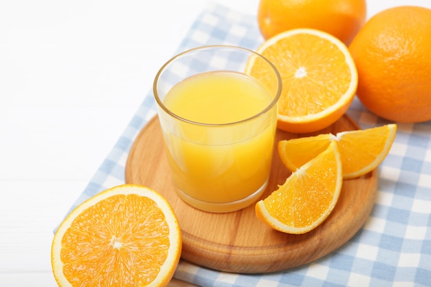 Orange juice in a glass oranges and orange slices on the table