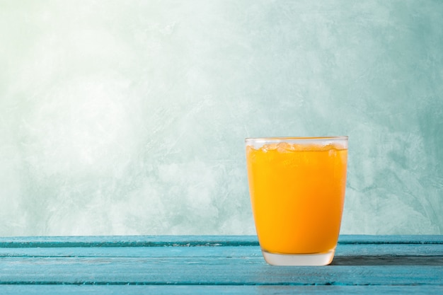 Orange juice in glass with ice on ocean blue wooden summer time concept.