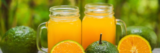 Orange juice and oranges with green peel on a wooden background banner long format