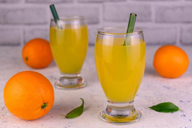 Orange juice in tall glasses and fresh oranges