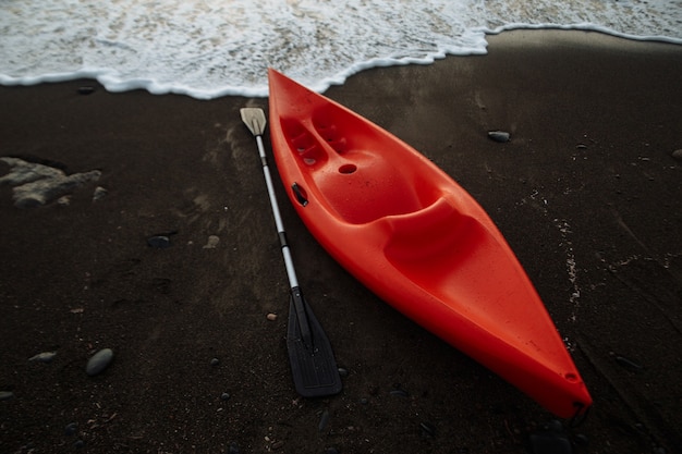 Orange kayak with an oar by the sea