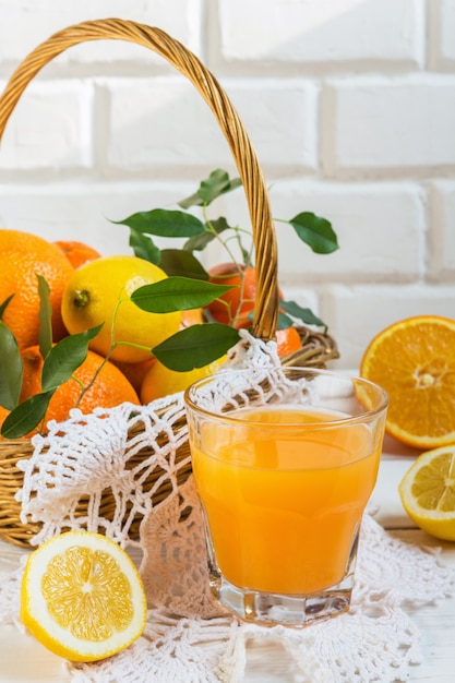 Orange lemon citrus fruits in a basket and juice on a light background, diet healthy food