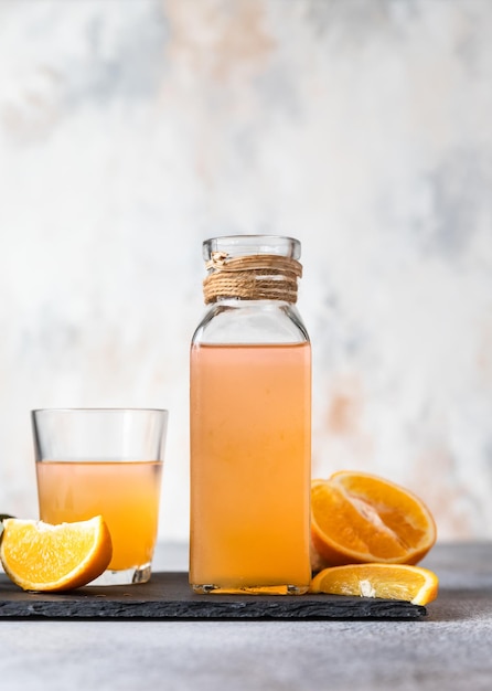 Orange lemonade in glass and bottle with fresh orange Refreshing drink Cocktail bar