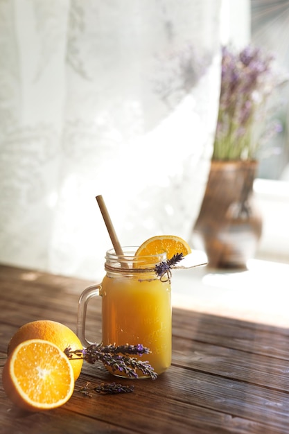 Orange lemonade in a mug on a wooden table by the window