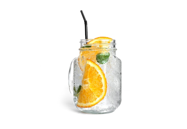 Orange lemonade with mint and ice in a clear mason jar isolated.