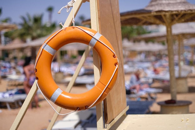 Orange lifebuoy weighing on hotel beach closeup