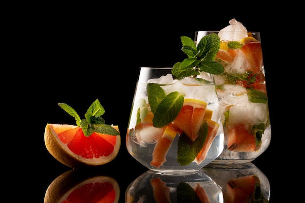 Orange and mint slice and glass with orange and mint ice drink isolated on black background