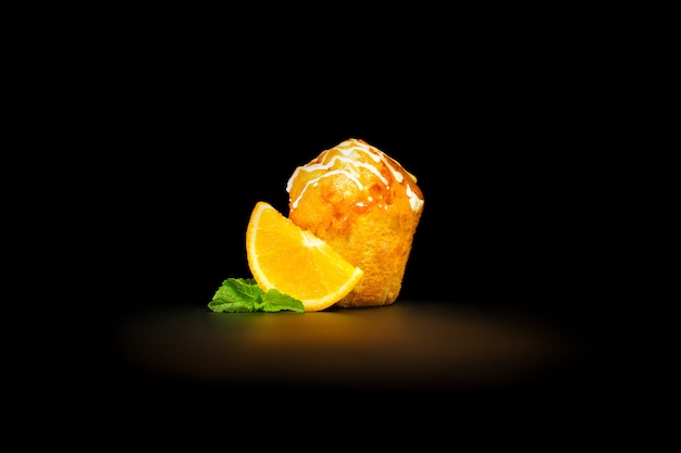 Orange muffin with a slice of orange and mint leaves, drenched with icing 