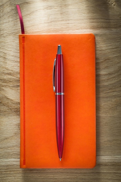 Orange notebook pen on wooden board