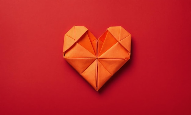 Orange origami heart on red background