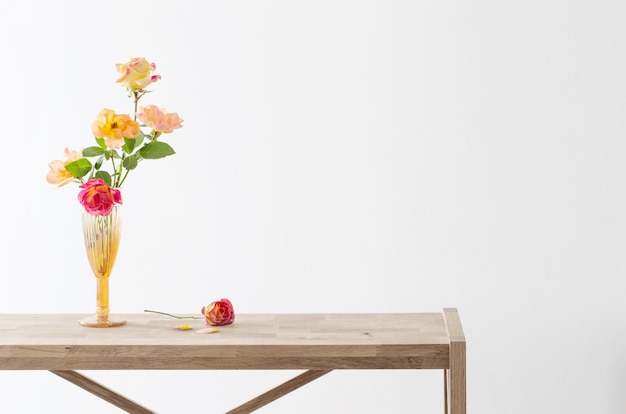 Orange and pink roses in glass vase in white interior