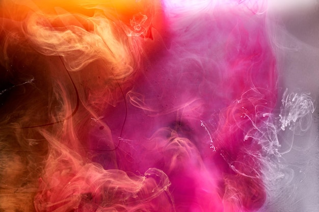 Orange pink smoke on black ink background colorful fog abstract swirling touch ocean sea acrylic paint pigment underwater