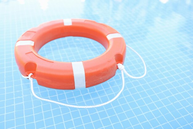 Orange plastic lifebuoy floating in pool closeup