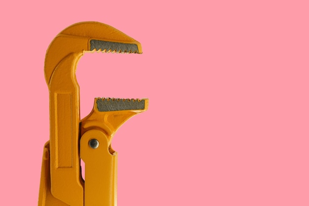 Orange plumber wrench on a pink background