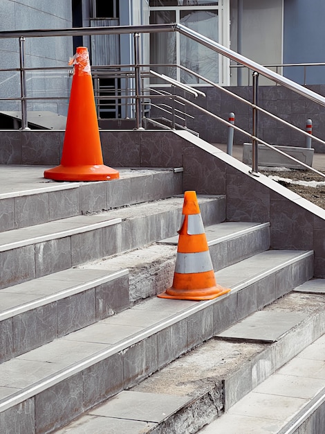 Orange protective cones on broken steps in office building warn of danger High quality photo