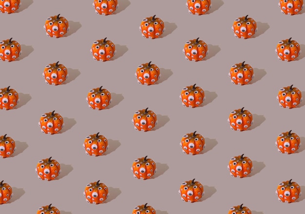 Orange pumpkin pattern with eyes on a gray background Halloween concept