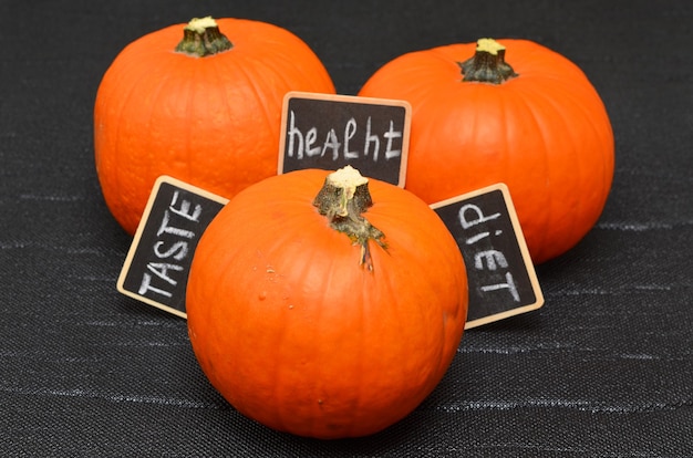 Orange pumpkins on a black background and tablets with the words taste health and diet