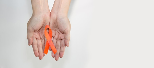 A Orange Ribbon in woman hand for Leukemia and Kidney cancer campaign to encourage and caring patient.