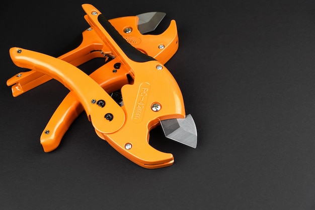 Orange scissors for cutting propylene pipes on a black background