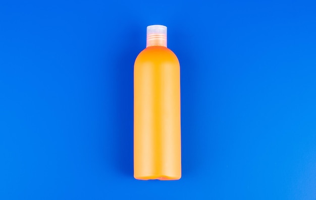 Orange shampoo bottle on blue background toiletries