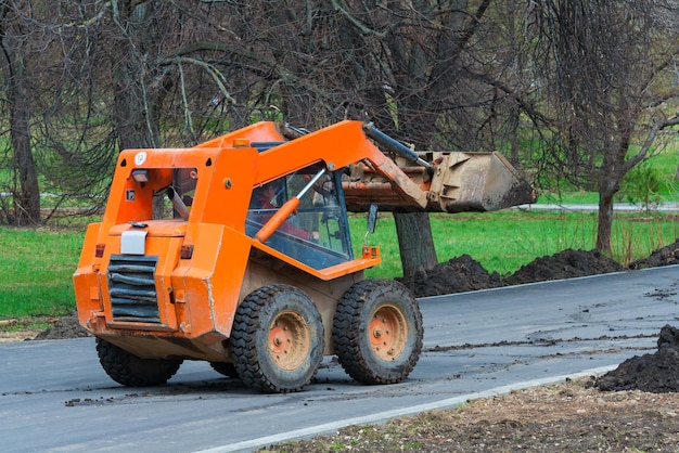 Orange Skid steer loader is on the road Works on the improvement of the park area