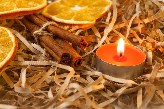 Photo orange slice and fragrant cinnamon sticks with a burning candle, close-up