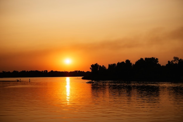 Orange sunset on the river with tree silhouettes