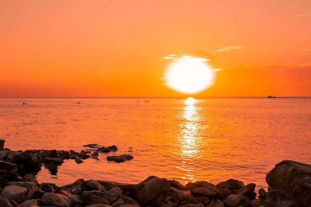 Orange sunset over the sea with a rocky shore Sea sunset landscape