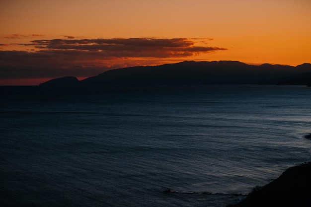 Orange sunset sky over the sea against the background of mountains