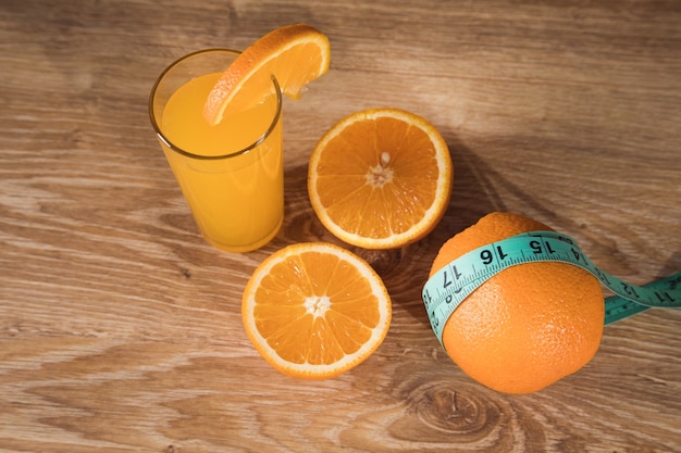 Orange on the table, measuring tape and orange juice