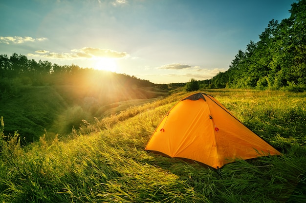 Orange tourist tent on a hill above the ravine