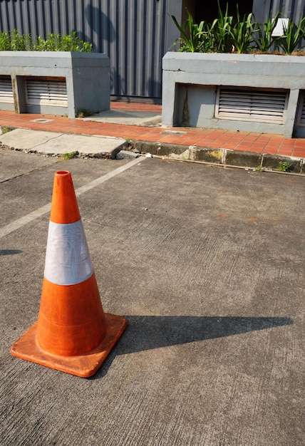 Photo orange traffic cone with white reflective paint on a parking area