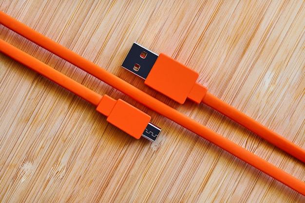 Orange USB cable for gadgets on a wooden table