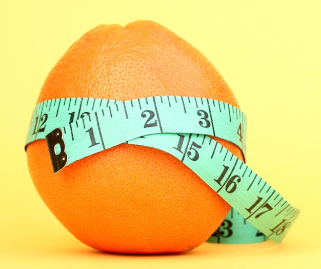 Orange with measuring tape on yellow background