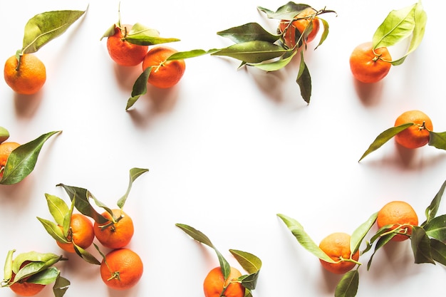 Oranges fruits composition with green leaves and slice on white wooden background, top view