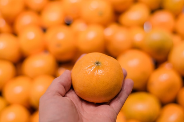 Oranges, mandarins background and texture. Hand pick up orange in market.