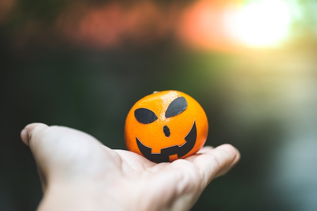 An oranges pumpkin face painting with scary on halloween party day on hand 